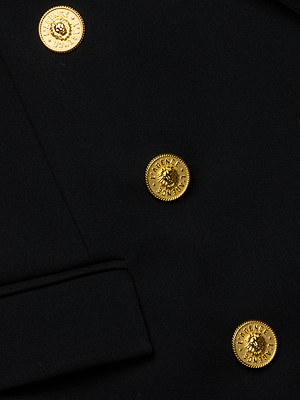 Close-up of the Cambrie Oversized Blazer by L'AGENCE in black, featuring three ornate gold lion's head buttons, decorative edges, and a stitched pocket flap on the left—a refined detail on this classic piece.
