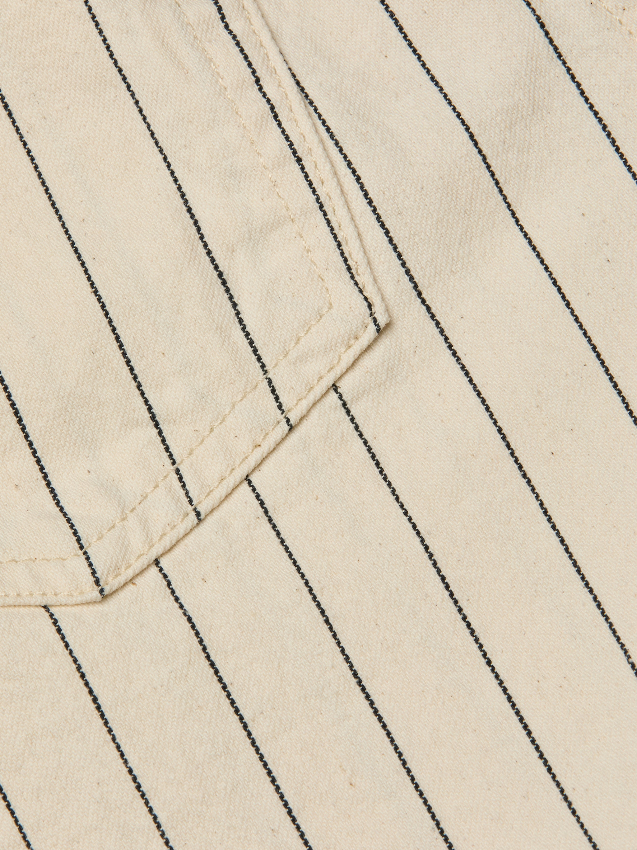 Close-up of the Lissania Short in beige, featuring thin vertical black pinstripes and visible stitching around the edge of a pocket.