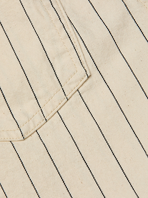Close-up of beige cotton twill with black vertical pinstripes and a pocket seam in the upper left, featured on the Lissania Short—ideal for a coastal-inspired look.