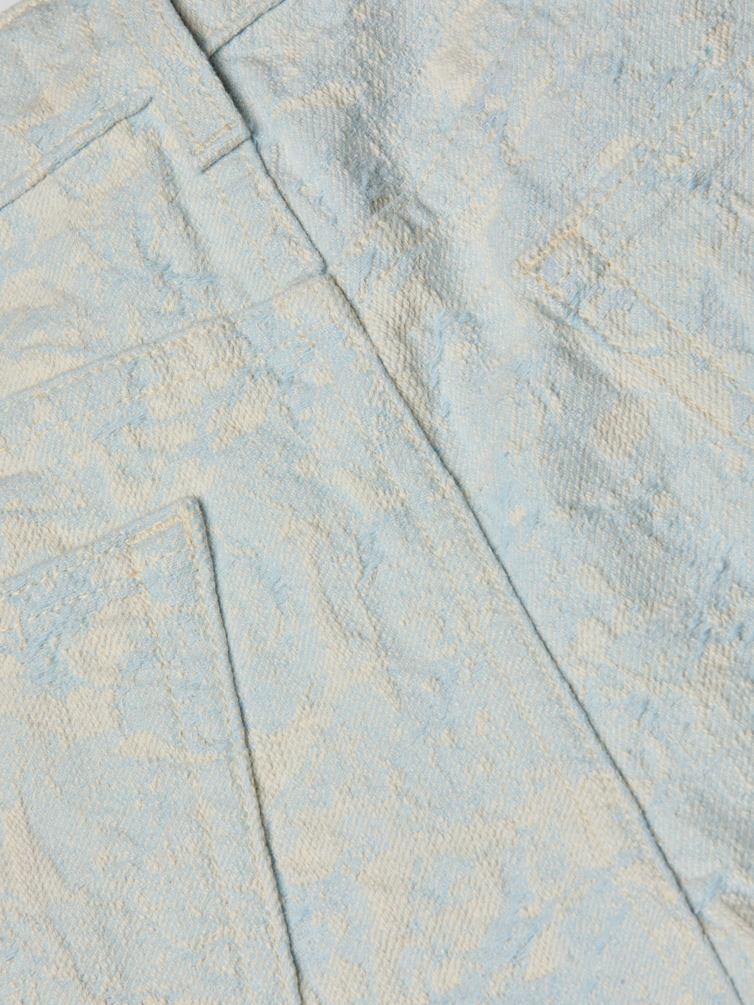 Close-up of light blue cotton jacquard fabric with a subtle pattern, featuring two pockets and seam details, shown on the Lissania Jacquard Short.