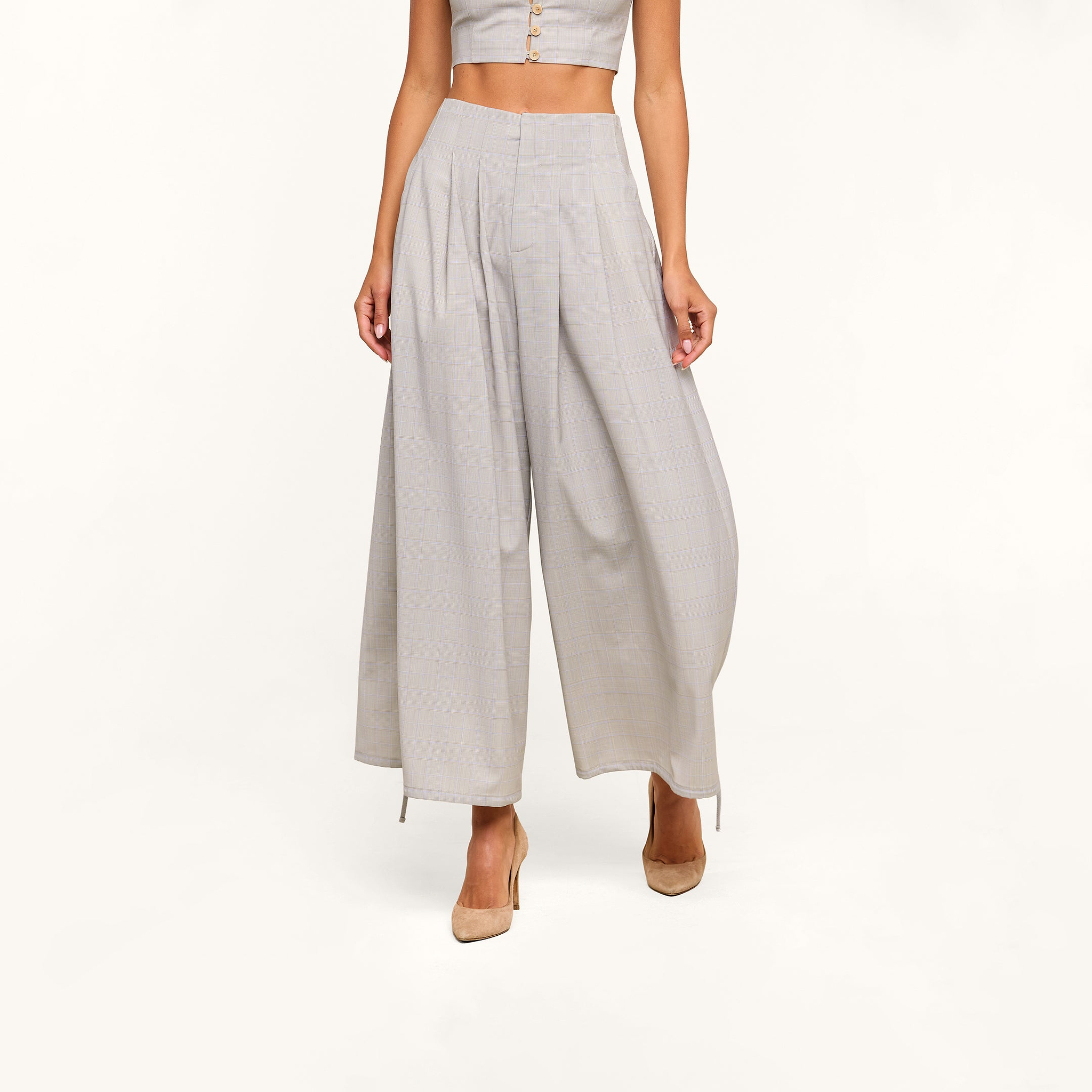 A woman wearing the Ysola Pant—ultra-high rise, wide-leg wool blend trousers in light gray—and beige heels stands against a plain white background. Her face is not visible in the image.