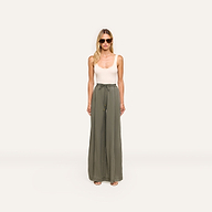 A woman in sunglasses and a white sleeveless top faces forward against a plain white background, wearing high-waisted olive green Connie Drawstring Trouser with a drawstring waistband.