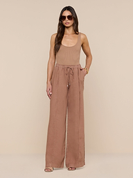 A woman wearing sunglasses, a sleeveless tan top, and the Connie Linen Drawstring Trouser—high-waisted, wide-leg vacation pants with a drawstring waistband—stands against a plain white background.