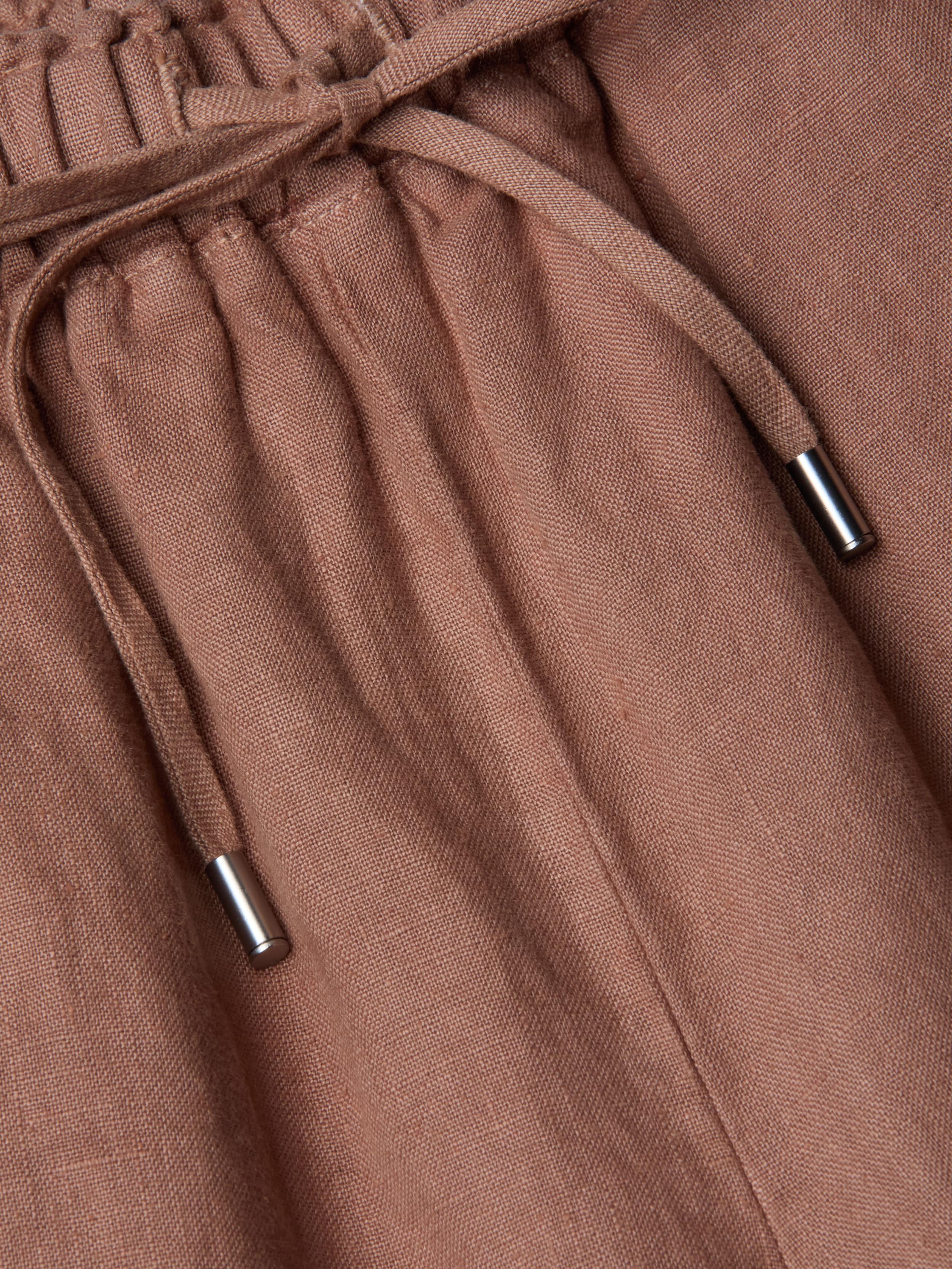 Close-up of the Connie Linen Drawstring Trouser in light brown, featuring a drawstring waistband with silver metal tips.