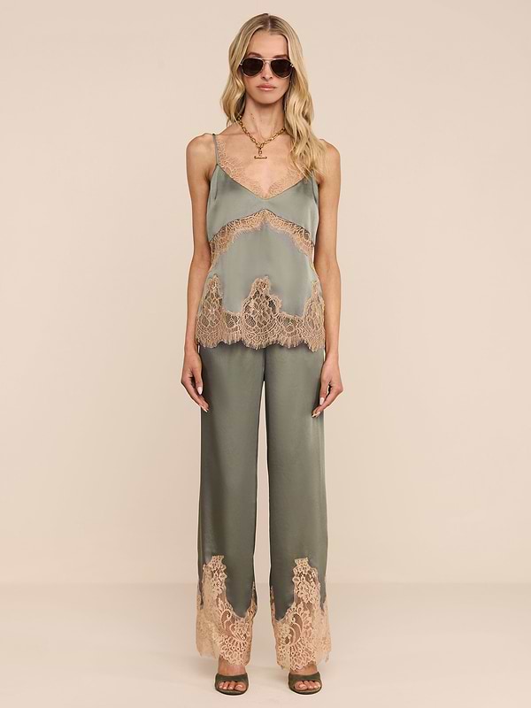 A woman stands against a plain white background wearing the Mirel Pant in olive green, featuring lace trim and a drawstring waist. She pairs it with a matching camisole, sunglasses, open-toe heels, and her long blonde hair.