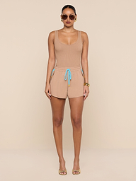 A woman stands against a white background, wearing a beige crepe nylon tank top and matching Grayson Nylon Shorts with a blue drawstring, paired with gold sandals, sunglasses, and gold bracelets.