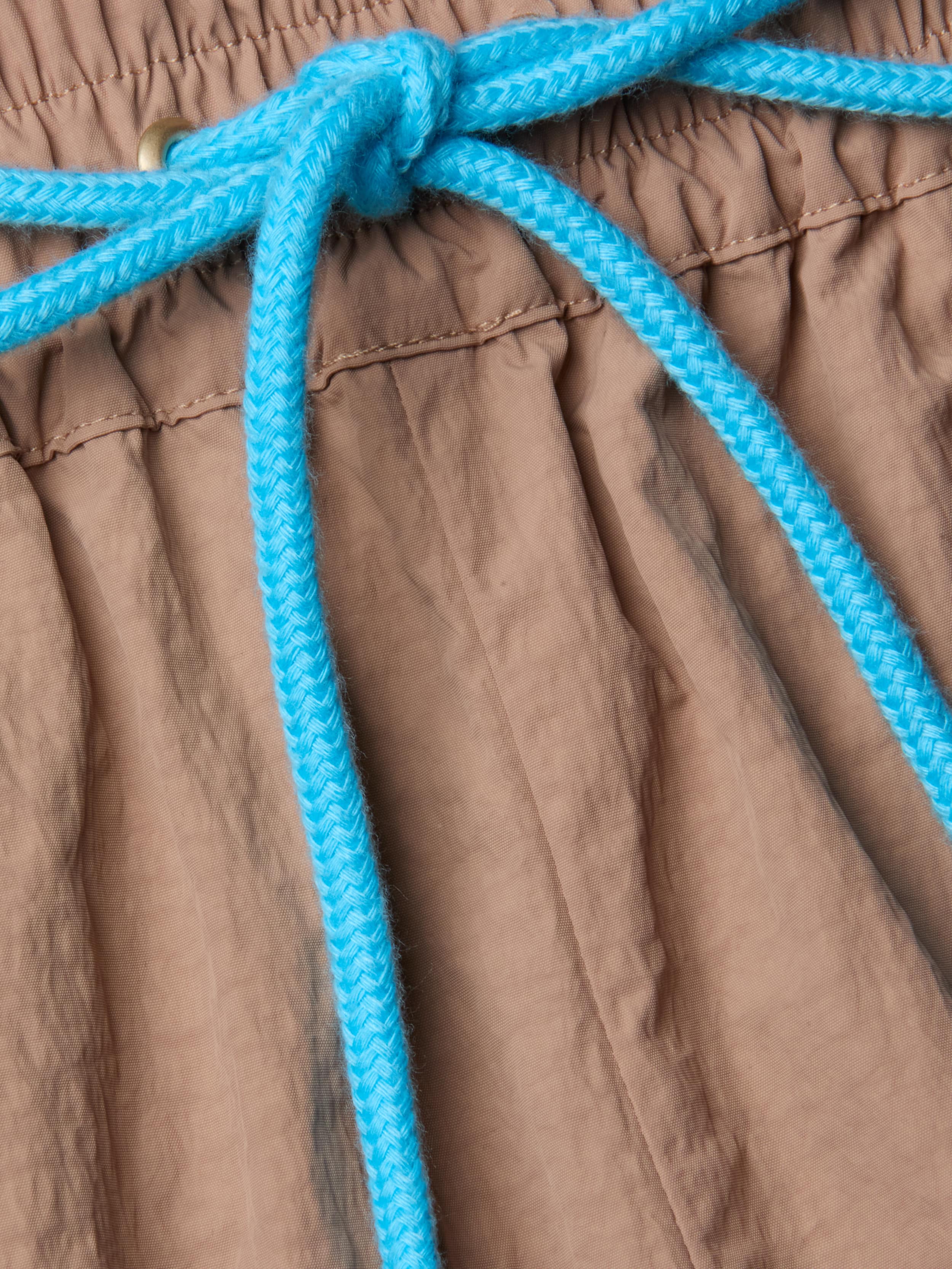 Close-up of the Grayson Nylon Short’s brown crepe nylon waistband, featuring a gathered, elastic texture and finished with a bright blue braided drawstring tied in a bow—a signature detail of this style.