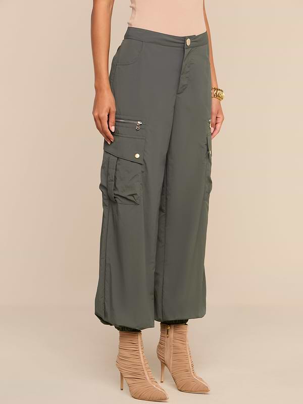 Wearing the Greer Nylon Jogger in ash olive green, featuring multiple cargo pockets, paired with beige high-heeled boots, a person stands against a neutral background.
