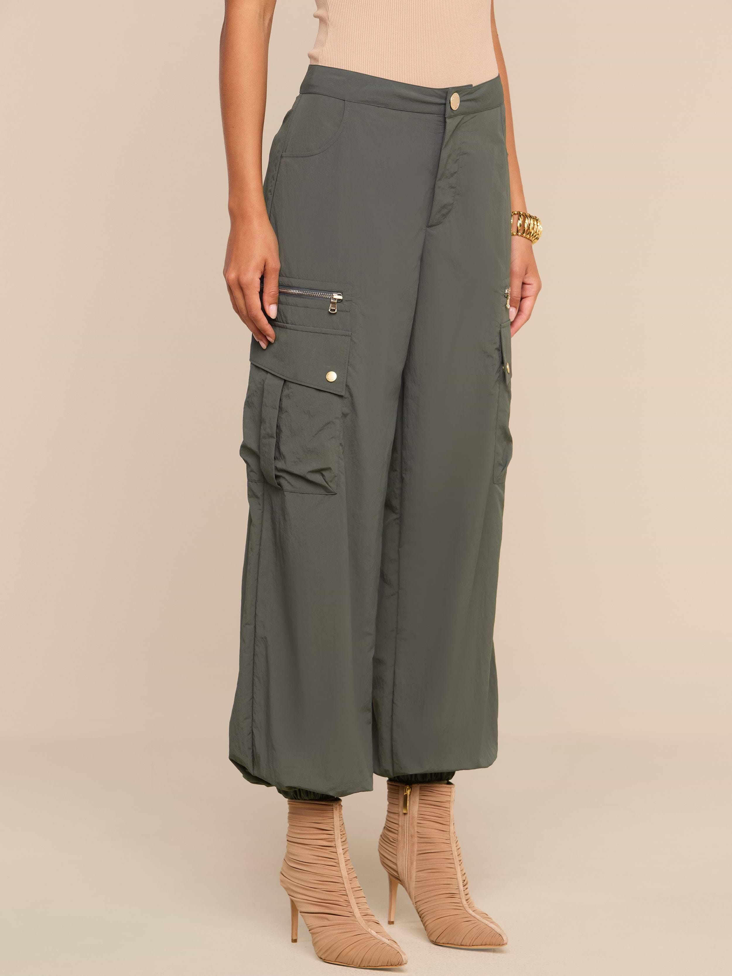 Wearing the Greer Nylon Jogger in ash olive green, featuring multiple cargo pockets, paired with beige high-heeled boots, a person stands against a neutral background.