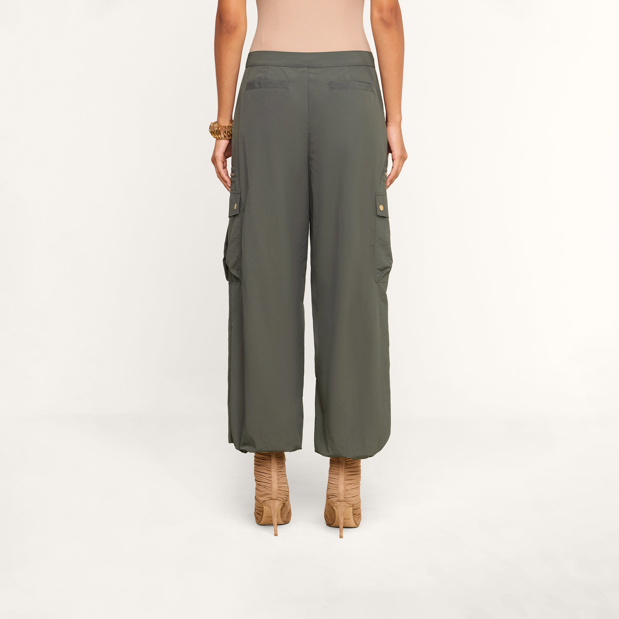 A person wearing the Greer Nylon Jogger in ash olive green and beige high-heeled sandals, standing with their back to the camera against a plain background.