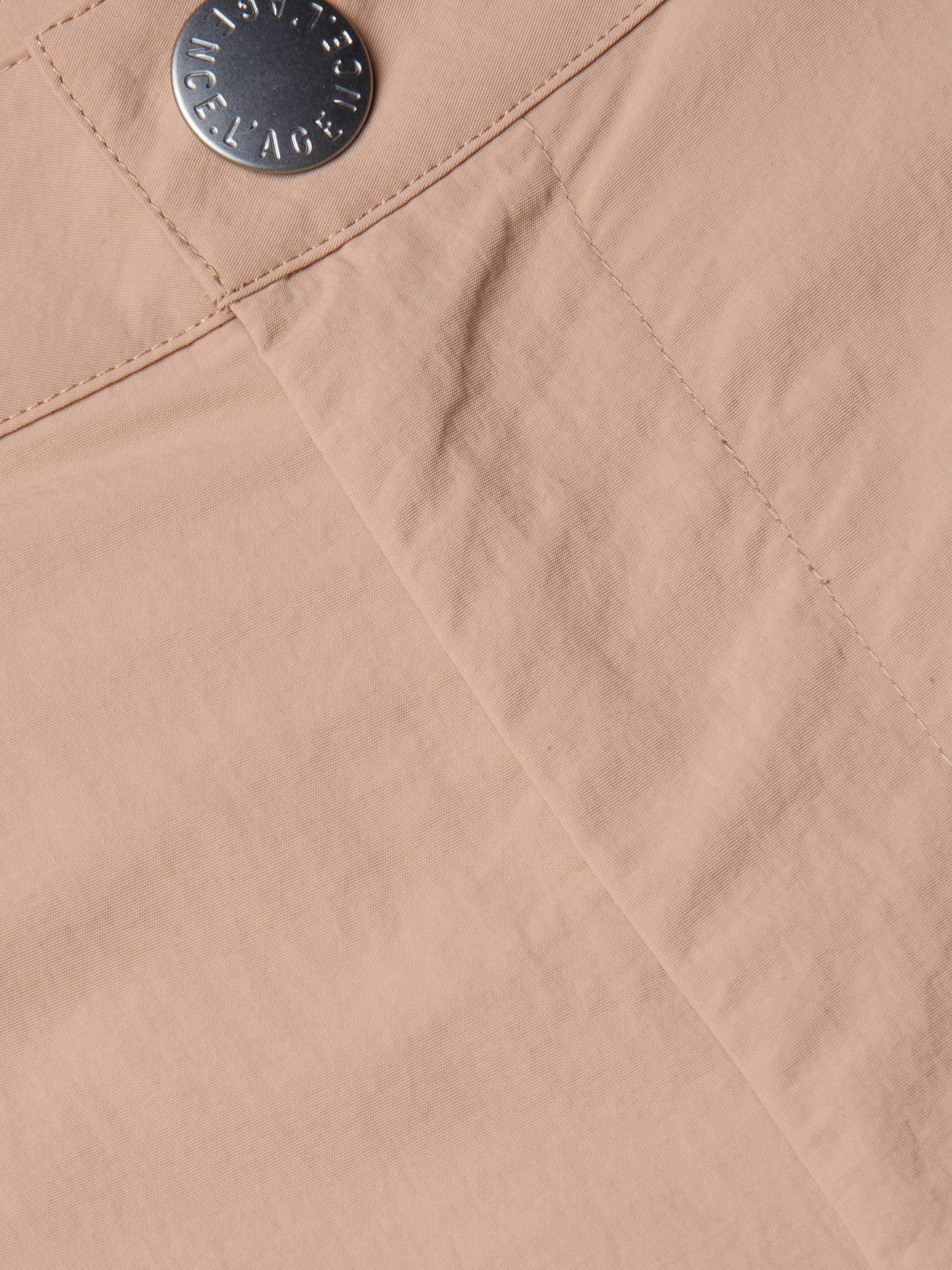 Close-up of the Greer Nylon Jogger in light beige fabric, showing visible stitching and a silver engraved button; features subtle cargo pockets for extra utility.