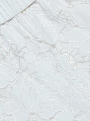 Close-up of white lace with a floral pattern and intricate stitched flowers and leaves, paired with pleated white fabric at the edge—reminiscent of cotton eyelet used in the lightweight Laina Eyelet Short.