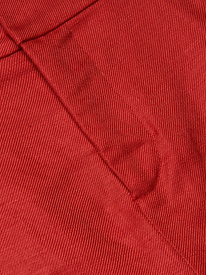 Close-up of red corduroy fabric with fine vertical ridges and a seam featuring a partially visible pocket—perfect texture inspiration for summer office looks or styling the Doretta Bermuda Short.