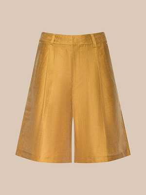 Le bermuda Doretta en lin mélangé, jaune dor, présente une taille haute, un tissu texturé brillant, des passants de ceinture et des plis cousus sur le devant, sur un fond beige uni.