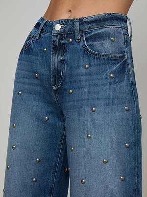 Close-up of a person wearing the Bex Studded Rodeo Jean—high-rise denim with front button, pockets, and evenly spaced metallic studs—shown against a plain neutral background.