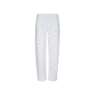 The “Bex Embellished Rodeo Jean” is a white, high-waisted denim featuring a straight leg cut and adorned with evenly spaced small silver grommet details across the front and sides. These high-rise jeans are displayed against a plain white background.