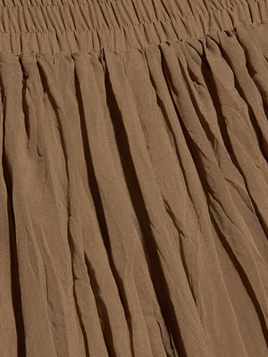 Close-up of the Ethel Pleated Pant in brown crinkle chiffon, featuring a gathered elastic waistband. With its slightly sheer, crinkled texture and vertical folds, these are perfect vacation pants for effortless summer style.