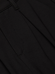 Close-up of the Akasha Bermuda Short in black stretch ponte fabric, featuring a seam, waistband with a belt loop, and pleated detailing.