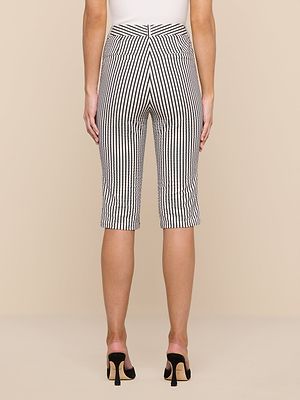 A woman is shown from the back wearing the Leni Pedal Pusher, featuring black and white vertical stripes, paired with a white top and black heels against a beige background.