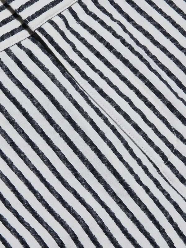 Close-up of the Leni Pedal Pusher’s black and white vertical striped cotton seersucker fabric, showcasing a visible seam and a folded edge that highlight its textured, patterned appearance.