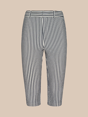 The Leni Pedal Pusher features navy blue and white vertical stripes on cotton seersucker, with belt loops, a front closure, and a tailored fit, shown against a beige background.