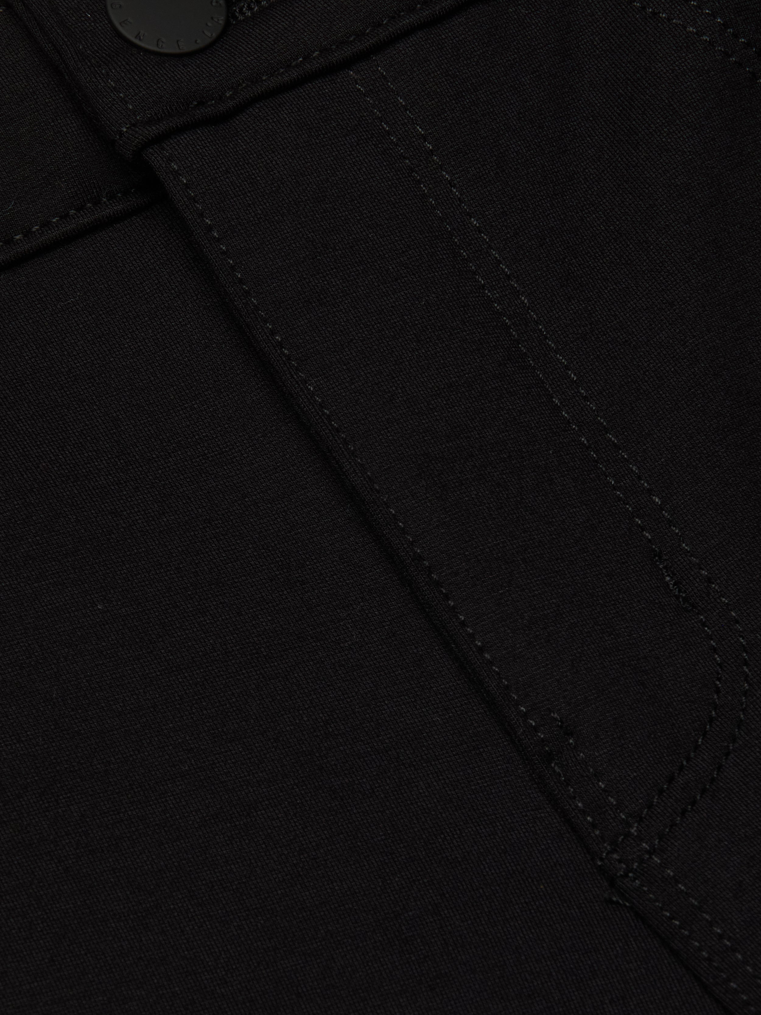 Close-up of the Amaris Pedal Pusher in black denim, highlighting a stitched seam, partial pocket detail, and a black button at the top—crafted for a body-hugging fit.