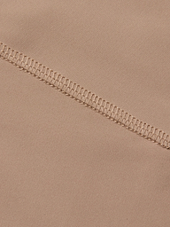 Close-up of beige fabric from the Velle Knit Panty, featuring a high waist design with a visible overlock stitch seam running diagonally, highlighting the intricate threadwork and smooth textile texture.