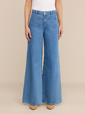 يظهر شخص واقفًا وذراعاه مسترخيتان على جانبيه، مرتديًا بنطال الجينز «Delcan Wide-Leg Jean» الذي يتميز بقصة عالية الخصر وجيوب أمامية ملتصقة، وذلك على خلفية بيج سادة.