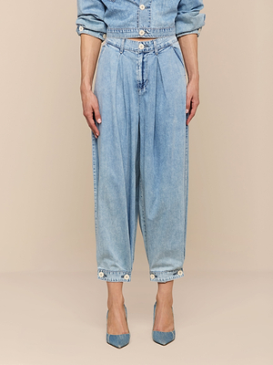 Portant le jean à jambes larges Elias - un palazzo en denim à taille haute et à plis - associé à une veste assortie et à des talons bleus à bouts pointus, ce look se détache sur un fond beige et constitue un style de transition idéal.