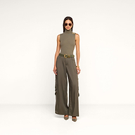 A woman wearing sunglasses, a sleeveless olive-green turtleneck top, and the Isolde Cargo Pant with pointed shoes stands against a plain white background.