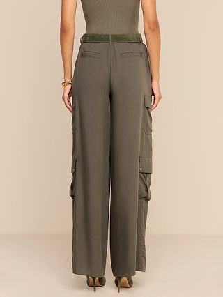 A person stands facing away, showcasing the back view of the Isolde Cargo Pant in olive green, featuring a high waist, wide-leg silhouette, lightweight Tencel fabric, and pockets.