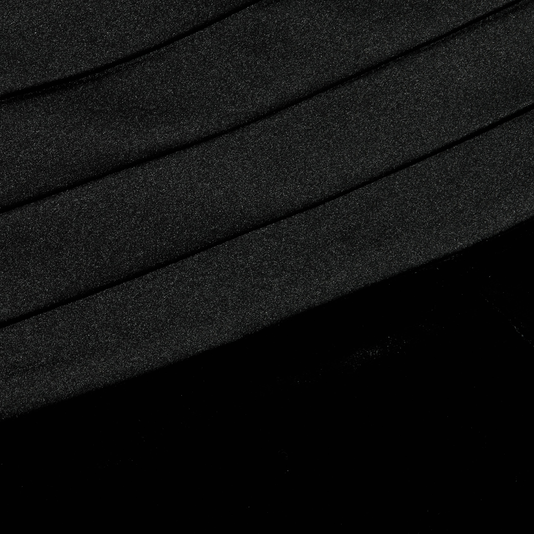 Close-up of the Prudence Cummerbund Trouser in black velvet, featuring diagonal, slightly curved folds. The soft and smooth texture is highlighted by subtle shadows and highlights that accentuate the contours of the pleats.