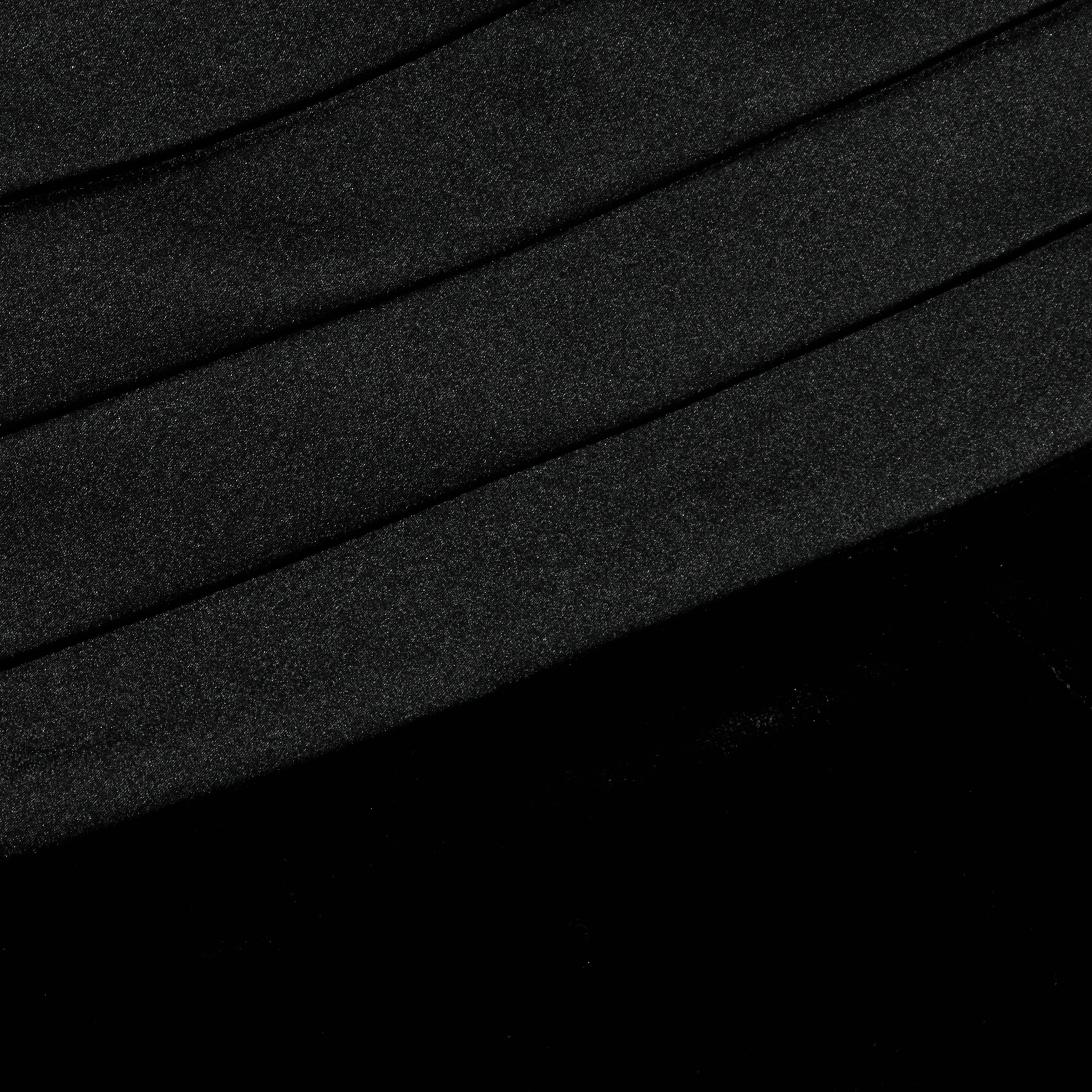 Close-up of the Prudence Cummerbund Trouser in black velvet, featuring diagonal, slightly curved folds. The soft and smooth texture is highlighted by subtle shadows and highlights that accentuate the contours of the pleats.