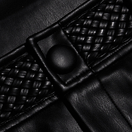 Close-up of the Virelle Short in black vegan leather, showcasing woven detailing and a round button. The texture and stitching are clearly visible, highlighting the striking contrast between smooth and braided sections—perfectly reflecting the quality finish of these high rise vegan leather shorts.