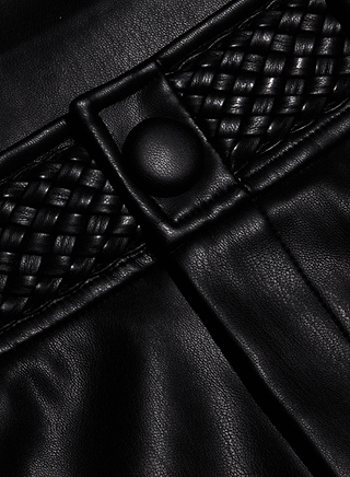 Close-up of the Virelle Short in black vegan leather, showcasing woven detailing and a round button. The texture and stitching are clearly visible, highlighting the striking contrast between smooth and braided sections—perfectly reflecting the quality finish of these high rise vegan leather shorts.