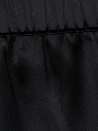 Close-up of the Joy Silk Lace Short in black, featuring a horizontal stitched seam near the top. The fabric above the seam is slightly gathered, forming soft folds and showcasing a smooth, matte texture—perfect for warm-weather style.