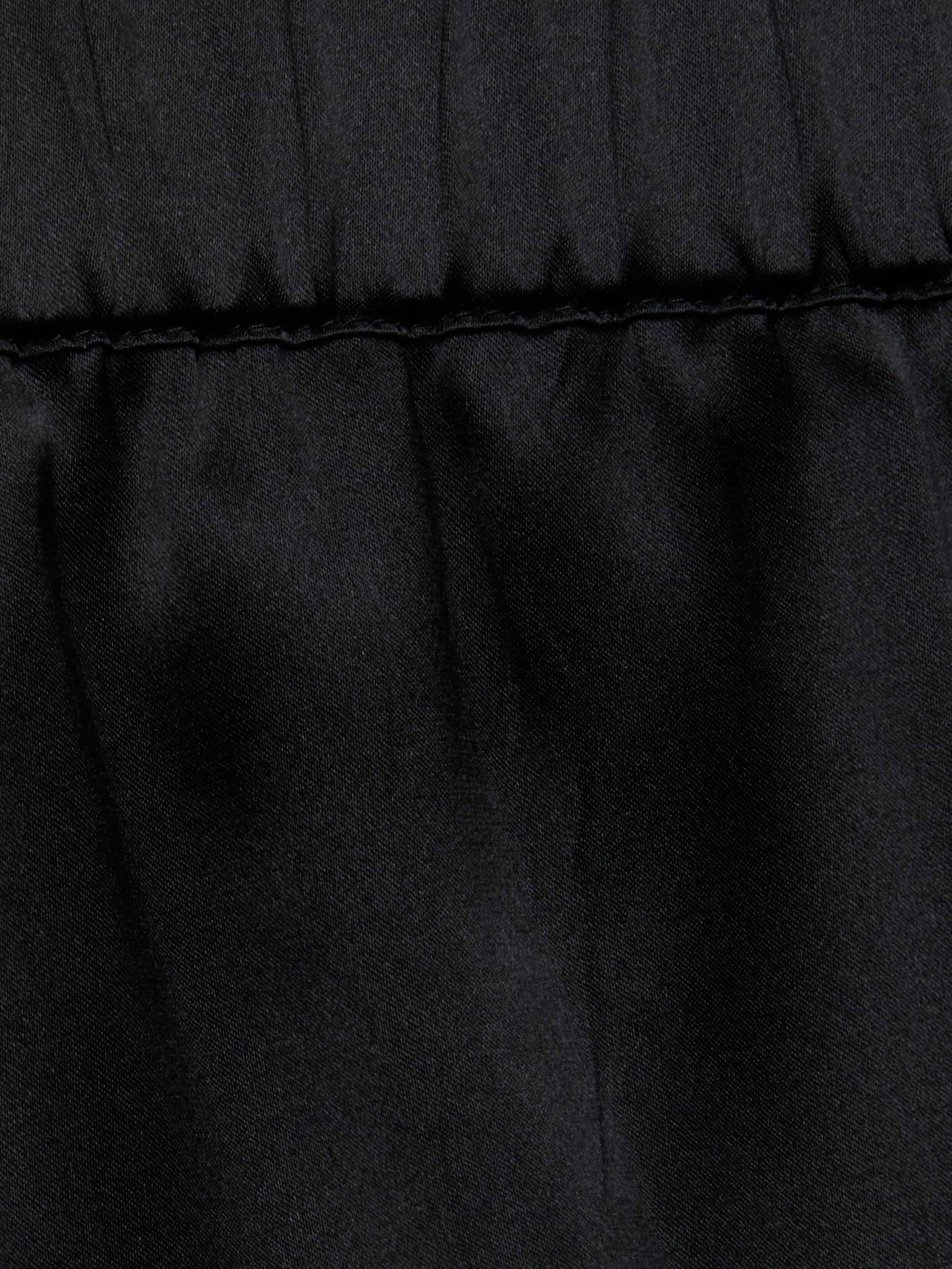 Close-up of the Joy Silk Lace Short in black, featuring a horizontal stitched seam near the top. The fabric above the seam is slightly gathered, forming soft folds and showcasing a smooth, matte texture—perfect for warm-weather style.