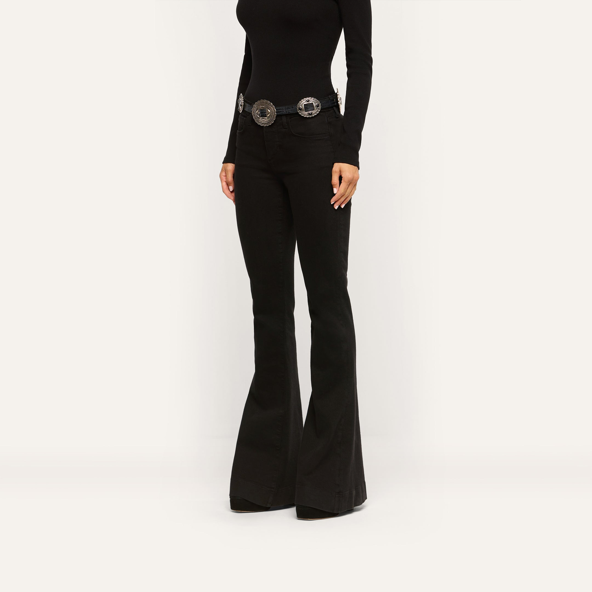 Her Story Flare Jean in black, styled with a silver-toned concho belt and a black long-sleeved top.