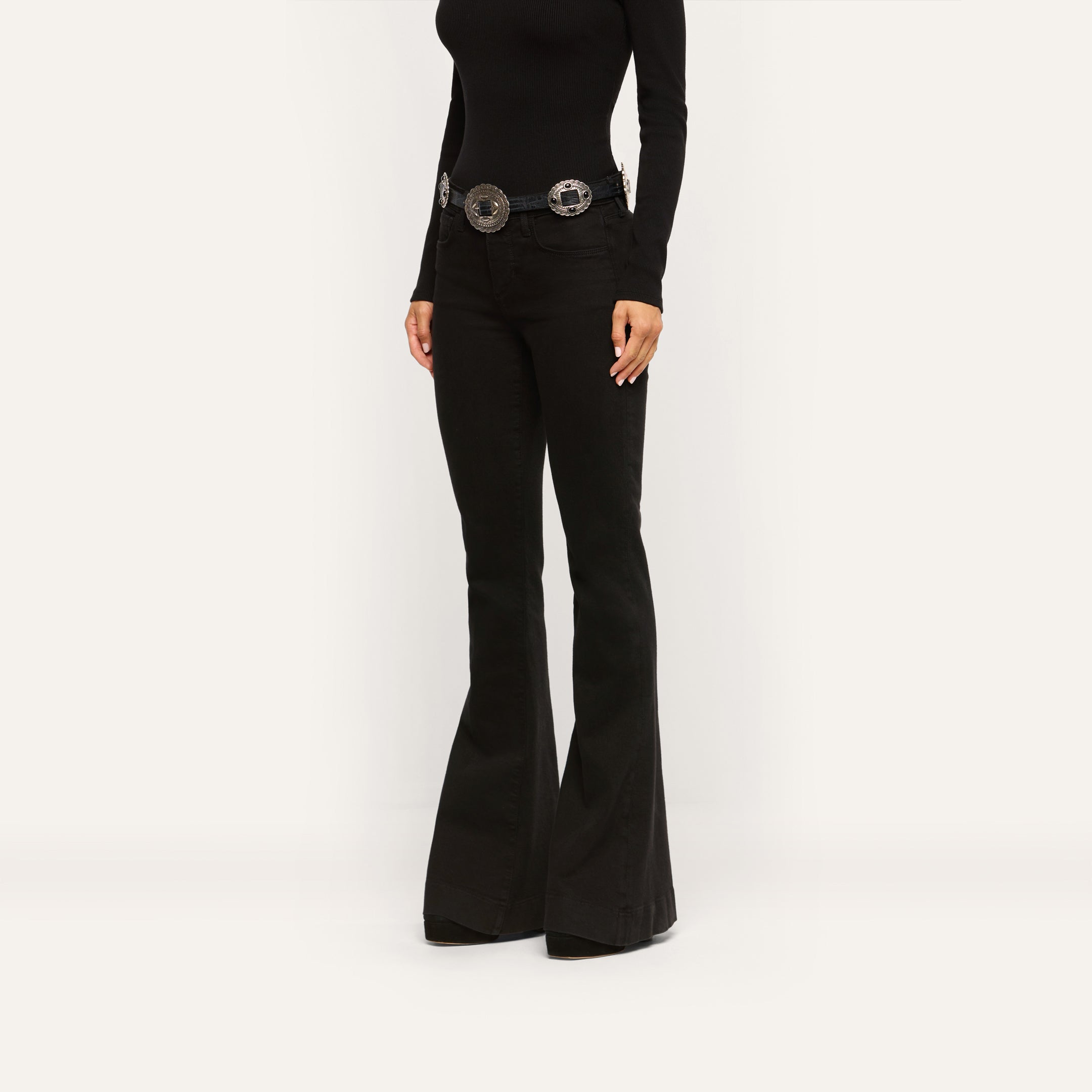 Her Story Flare Jean in black, styled with a silver-toned concho belt and a black long-sleeved top.