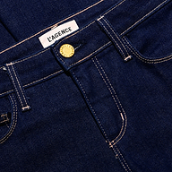 Close-up of dark indigo, low-rise Her Story Flare Jean featuring a gold-tone button fly and a white brand label at the waistband.
