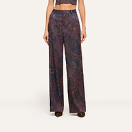 Wearing the Livvy Trouser—a high-rise, wide-leg pant in a dark midnight paisley print—paired with the matching cropped top and brown shoes, this person stands against a plain light background.