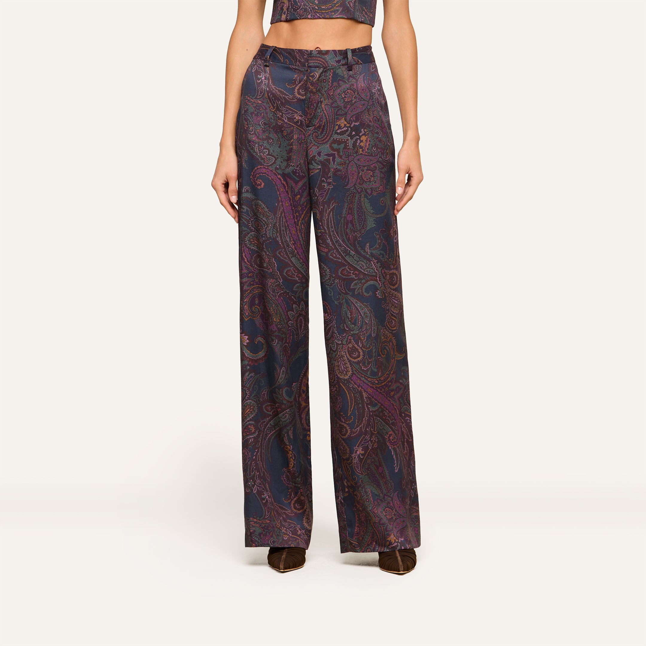 Wearing the Livvy Trouser—a high-rise, wide-leg pant in a dark midnight paisley print—paired with the matching cropped top and brown shoes, this person stands against a plain light background.
