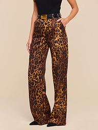 A woman is shown from torso to feet wearing the Livvy Trouser, which features a high-waisted, wide-leg silhouette in tan leopard print, paired with a black top and pointed black shoes against a plain background.