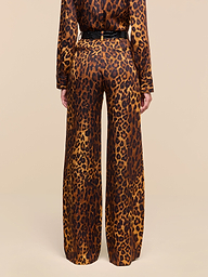 A person stands with their back to the camera, wearing the Livvy Trouser and a matching long-sleeve top in a tan leopard print pattern against a plain white background.