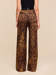 A person stands with their back to the camera, wearing the Livvy Trouser—high-waisted, straight-leg tan leopard print pants—paired with a black top against a plain white background.