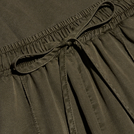 Close-up of the Chandler Cargo Pant in olive green, featuring an elastic waistband with a tied drawstring bow at the center. The lightweight fabric has a slightly textured appearance.