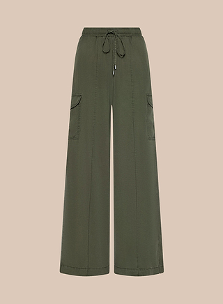 The Chandler Cargo Pant in olive green features a wide-leg silhouette, elastic drawstring waist, oversized side pockets, and visible stitching details, displayed against a light beige background.