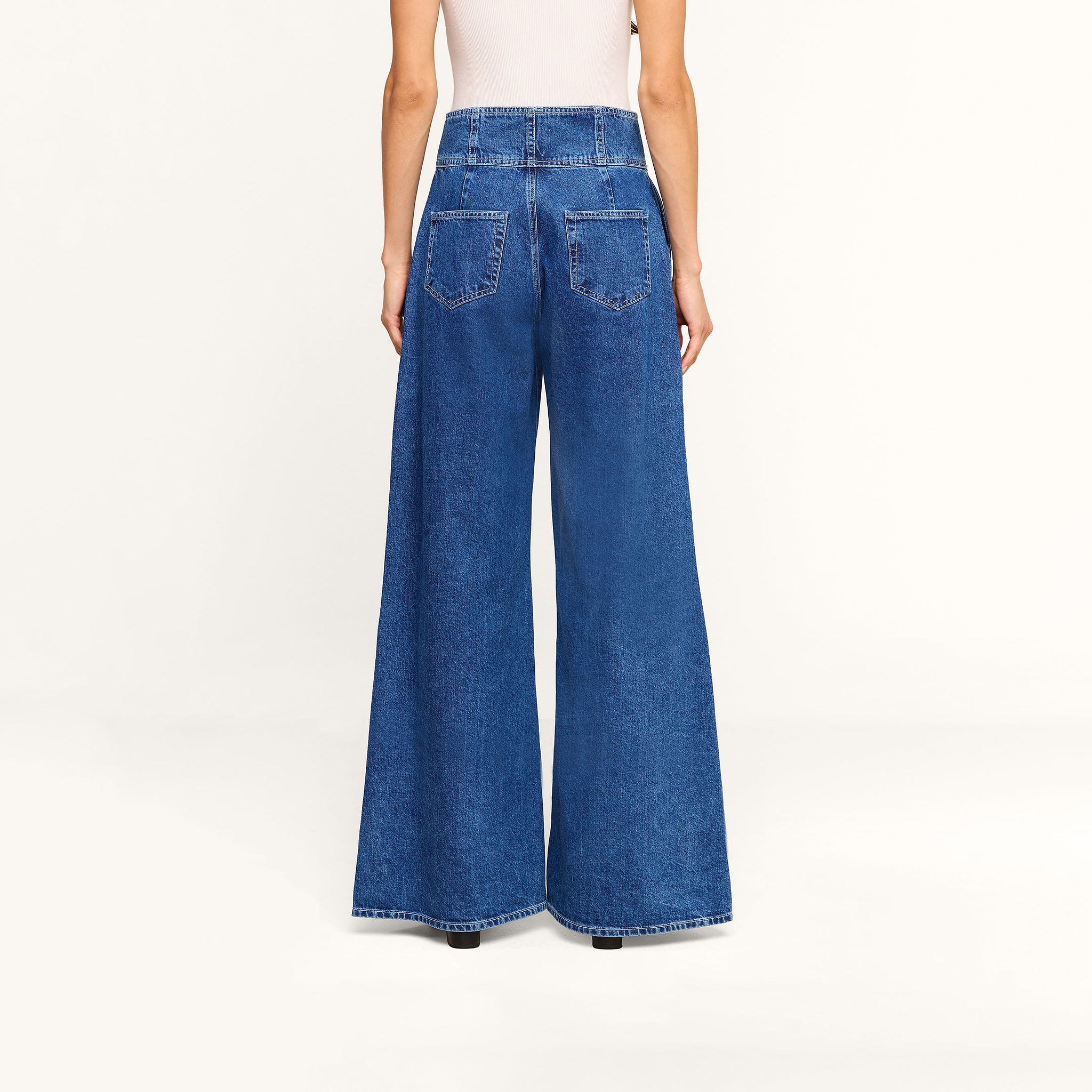 Back view of Sonja Corset Jean, ultra high-rise, wide-leg blue jeans featuring a corset-style waistband.