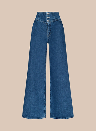 The Sonja Corset Jean is an ultra high-rise, wide-leg blue denim pant with a corset-inspired waistband and three metallic buttons at the waist, displayed against a plain beige background.