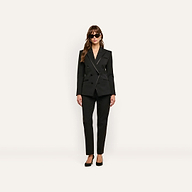 A person wearing a black double-breasted blazer with satin lapels, matching Rebel Trouser slim-straight trousers, and black high heels.